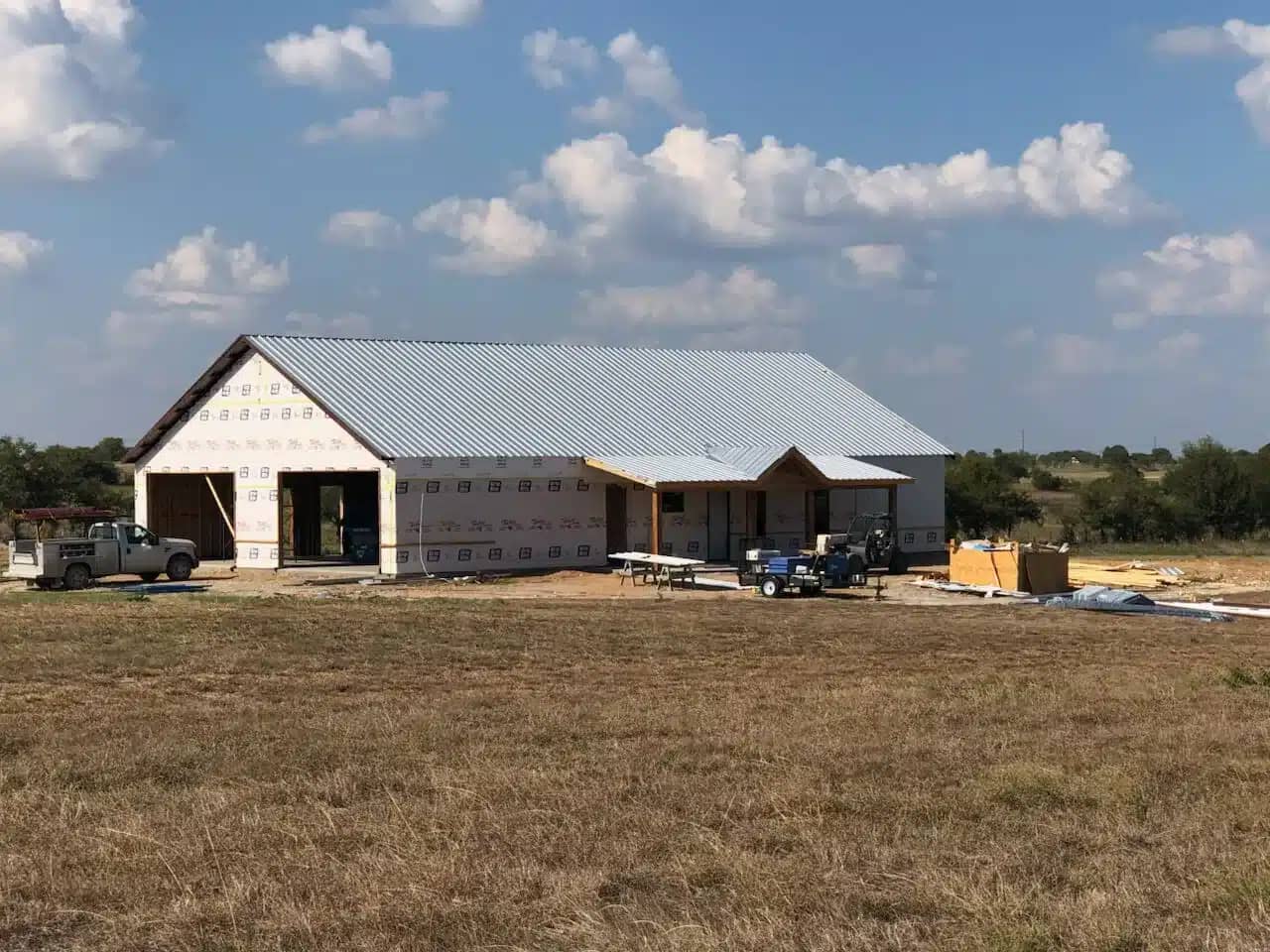 Custom metal-roof barndominium against a wide rural landscape.